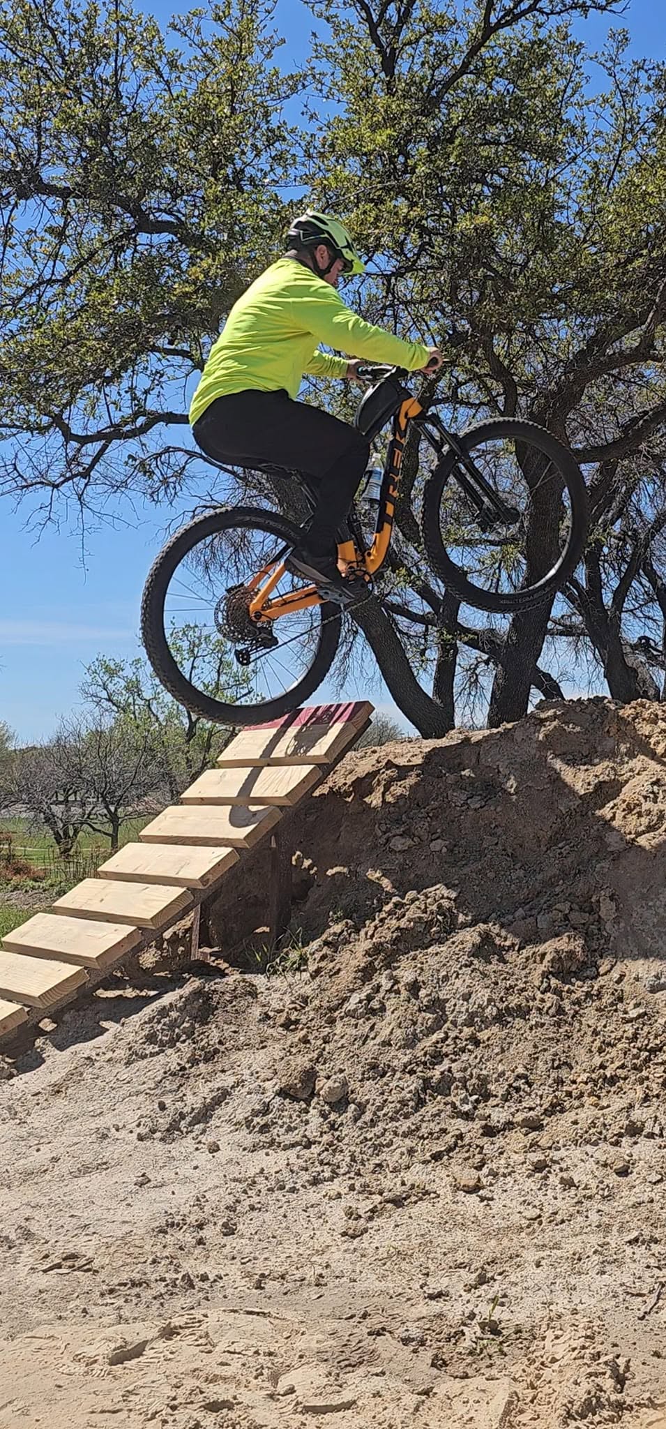A mountain biker riding over a rocky trail feature.